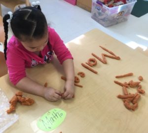 Girl spelling her name with playdough